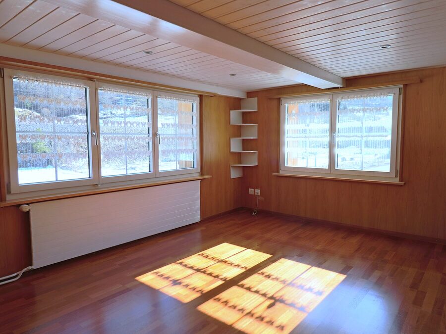 Helles Eckzimmer mit Fensterfront und Blick ins Tal